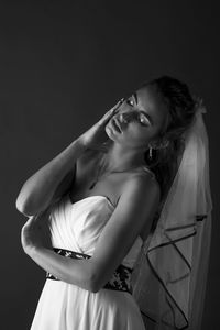 Young woman looking away while standing against black background