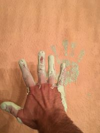 Man with paint on hand against wall