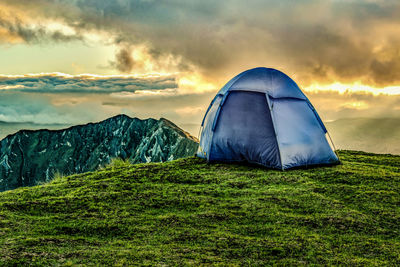 Tent on mountain against sky during sunset