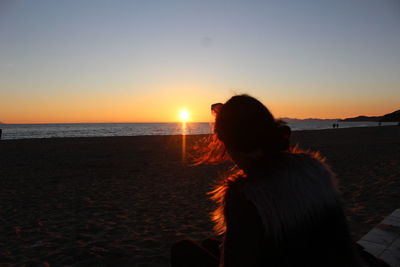 Rear view of a silhouette woman on beach at sunset