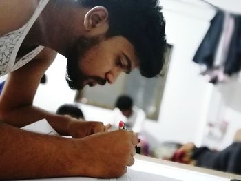 Side view of young man looking through camera