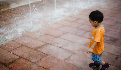 High angle view of boy standing on footpath