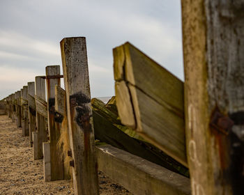 Wooden post amidst fence against sky
