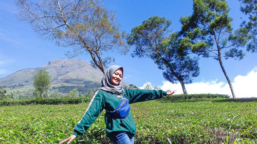 Full length of smiling young woman standing on field