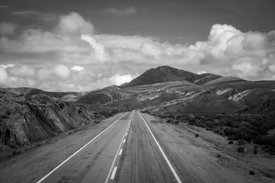 Road leading towards mountains against sky