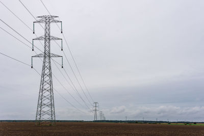 Extra high voltage overhead power line on large pylons, cloudy sky and copy space.