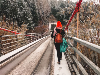 Rear view of man walking on footbridge