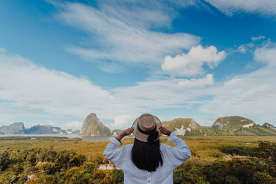 Rear view of woman wearing hat while looking at landscape against sky