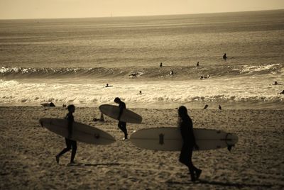 Men with surfboards walking on sea shore at beach