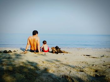 Rear view of people at beach against sky