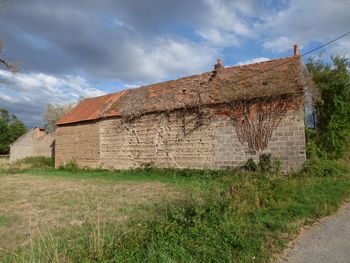 Old house on field against sky