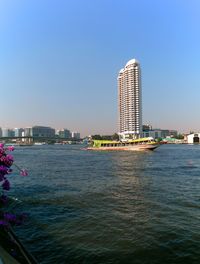 Sea by modern buildings against clear sky