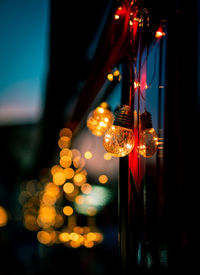 Close-up of illuminated light bulbs hanging at night