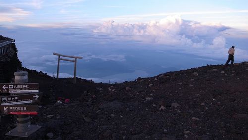Man standing on rock against sky