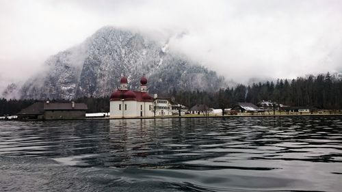 Scenic view of lake by building against sky during winter