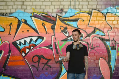 Full length of man standing against graffiti wall