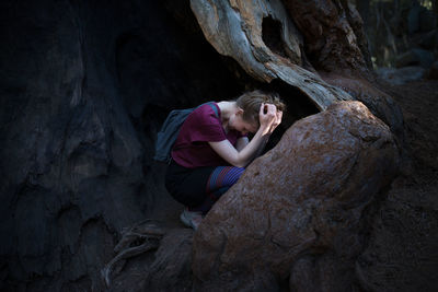 Tensed woman crouching on rock