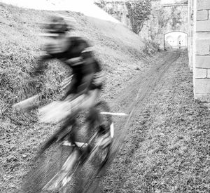 Blurred motion of man riding bicycle on road