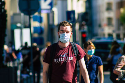 Portrait of young man standing on street in city