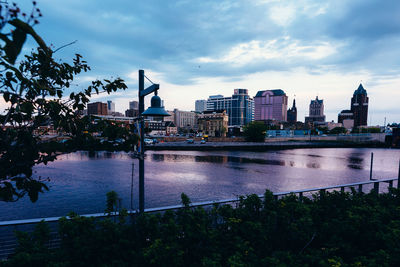 City at waterfront against cloudy sky