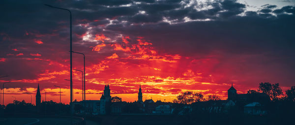 Silhouette buildings against dramatic sky during sunset