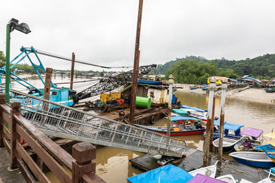 Fishing boats moored in river against sky