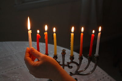 Cropped image of person lighting candles on table