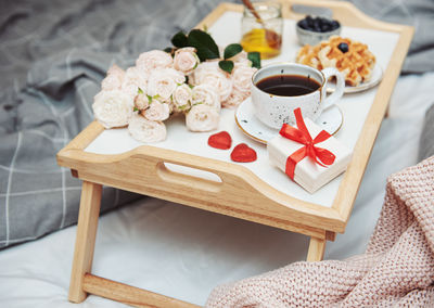 Romantic breakfast with coffee, waffles, gift box and rose flowers.