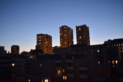 Illuminated buildings against clear sky at night