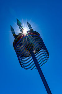 Low angle view of illuminated flag against blue sky on sunny day