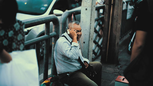Man looking at camera while sitting on mobile phone