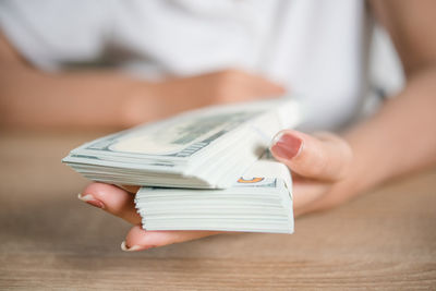 Midsection of businesswoman holding currency on table