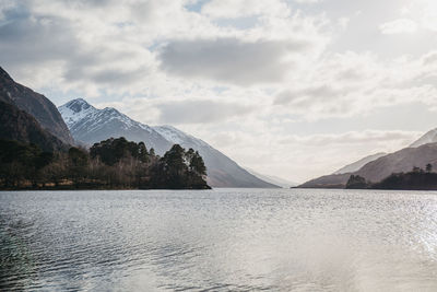 Scenic view of lake by mountains against sky