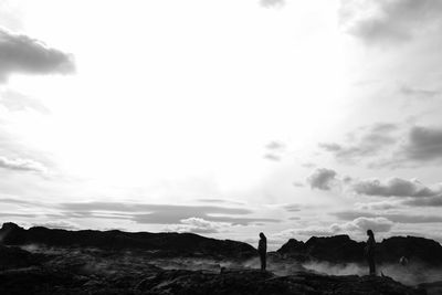 Rear view of silhouette people walking on mountain against sky