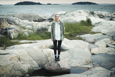 Full length portrait of wonderlust woman standing on rock