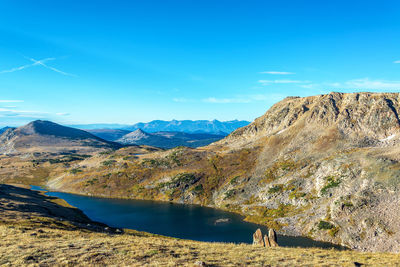 Scenic view of lake and mountains against blue sky