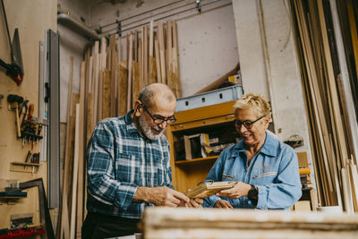 Male and female senior entrepreneurs discussing over frame at repair shop