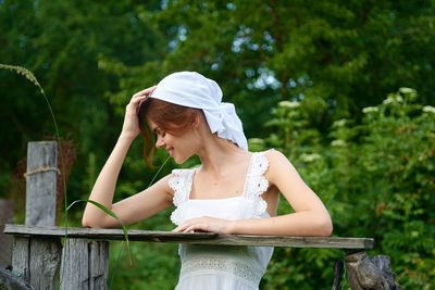 Side view of young woman sitting on railing