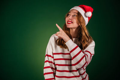 Portrait of young woman standing against blue background