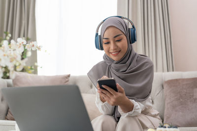 Young woman using phone while sitting at home