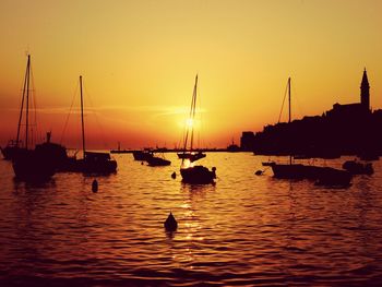 Boats sailing in sea at sunset