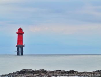 Lighthouse by sea against sky