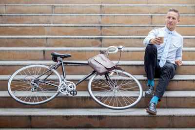 Man sitting on bicycle against wall