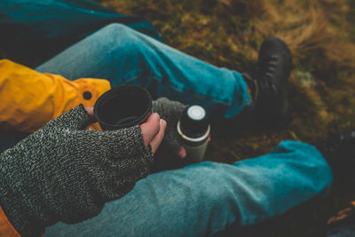 Low section of man holding bottle cap on field