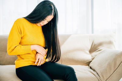 Midsection of woman sitting on sofa at home