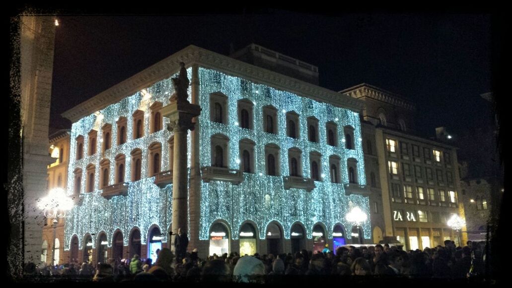 illuminated, night, architecture, large group of people, built structure, building exterior, transfer print, men, lifestyles, person, leisure activity, city, crowd, auto post production filter, city life, lighting equipment, building, mixed age range, travel destinations