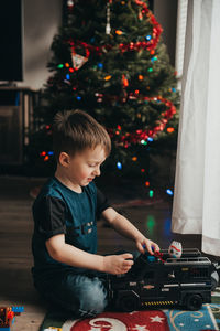 Full length of boy playing with toy against christmas tree at home