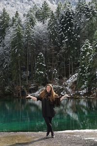 Woman standing against lake in forest