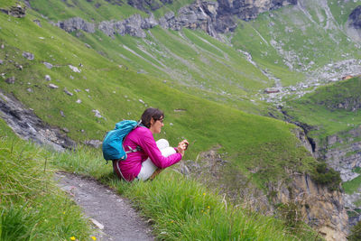 Rear view of woman sitting on mountain