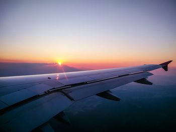 Close-up of airplane wing against sky during sunset